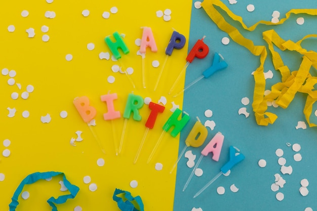 Velas de feliz cumpleaños con confeti y serpentinas de fiesta en azul y amarillo. concepto divertido de la fiesta de cumpleaños feliz.