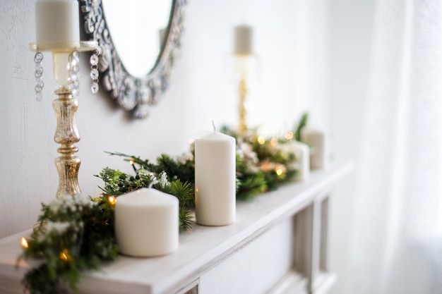 velas y guirnalda de Navidad en una chimenea blanca