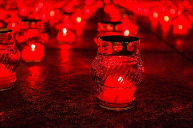 Foto velas de la iglesia encendidas en candelabros rojos transparentes.