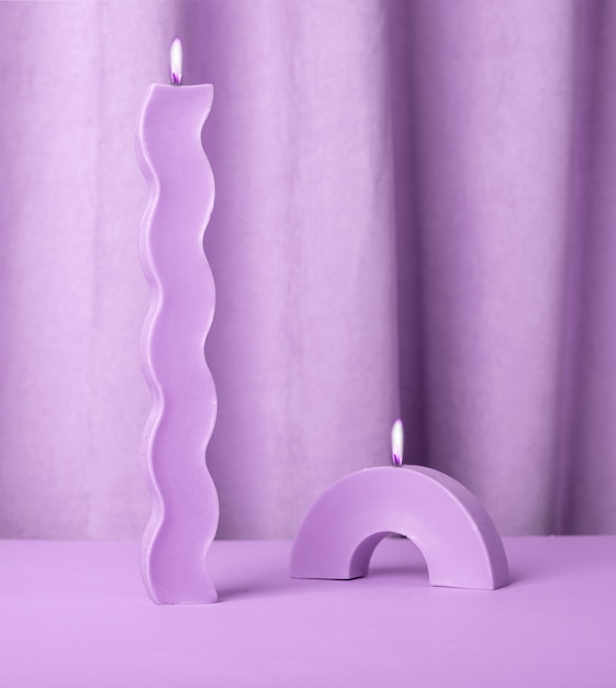 Velas moradas modernas de formas de onda y arco sobre fondo violeta decoración interior foto de alta calidad