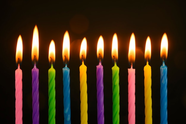 Velas multicolores arden en un pastel de cumpleaños