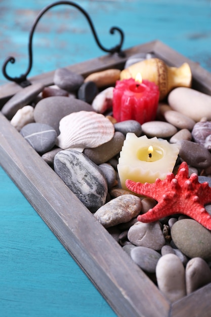 Foto velas na bandeja vintage com seixos do mar, estrelas do mar e conchas do mar no fundo de madeira