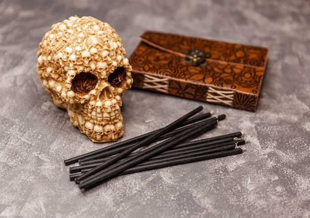 Velas negras de libro antiguo con calavera en ritual mágico de mesa de bruja