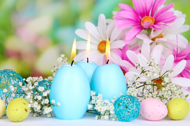 Velas de Pascua con flores sobre fondo brillante