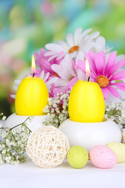 Velas de Pascua con flores sobre fondo brillante