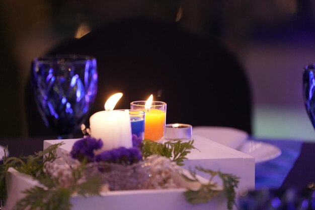 Las velas románticas están decoradas en la mesa con una caja cuadrada de madera blanca y un arbolito encima.