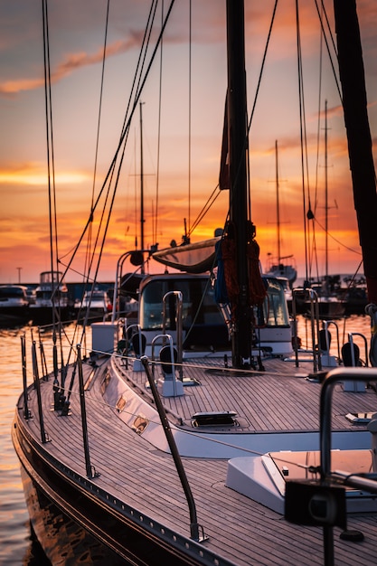 Veleiro com deck de madeira em pé na Marinha ao pôr do sol