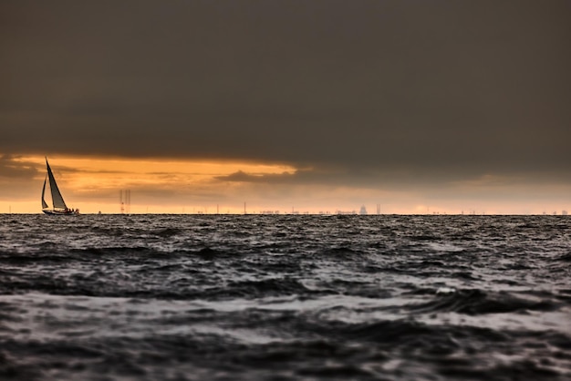 Veleiro no mar em tempo tempestuoso nuvens tempestuosas céu laranja céu vela regata grandes ondas de água