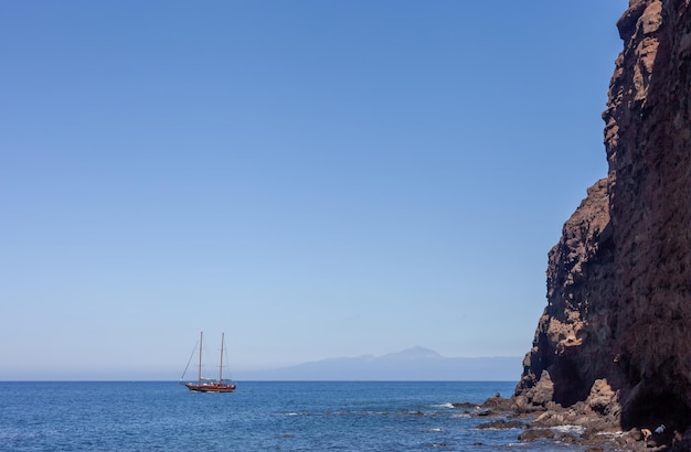 Un velero anclado junto a un acantilado en una playa tranquila en la isla española de Gran Canaria