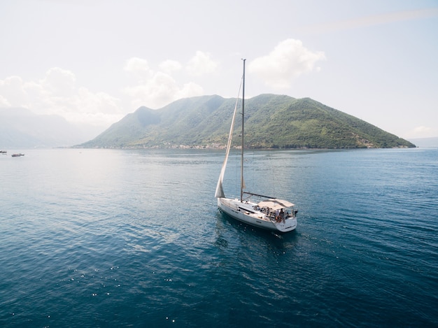 Velero blanco sobre el agua cerca de las montañas de la ciudad de Perast.