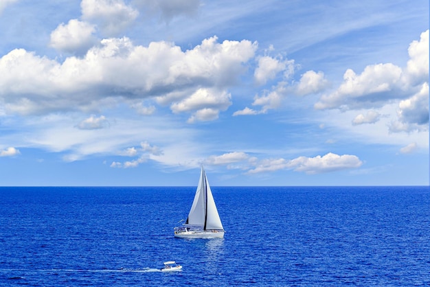 un velero está navegando en el océano con nubes en el cielo