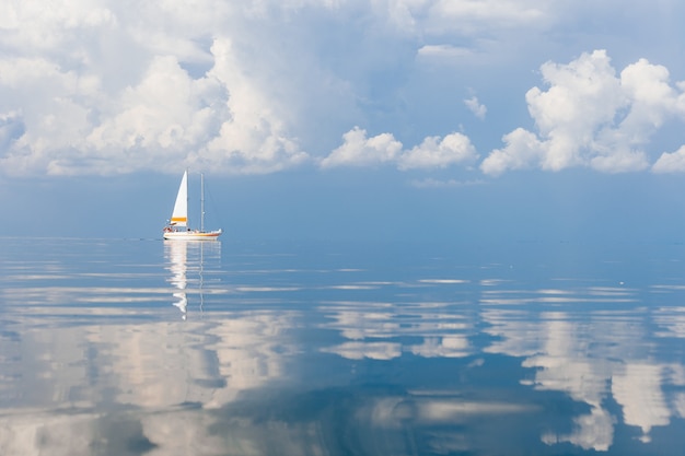 Velero en el mar en un día soleado en el fabuloso cuento de hadas pintoresco paisaje marino con nubes reflejadas en el agua.