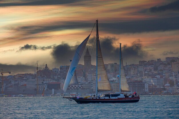 Foto un velero está navegando en el agua con una ciudad en el fondo