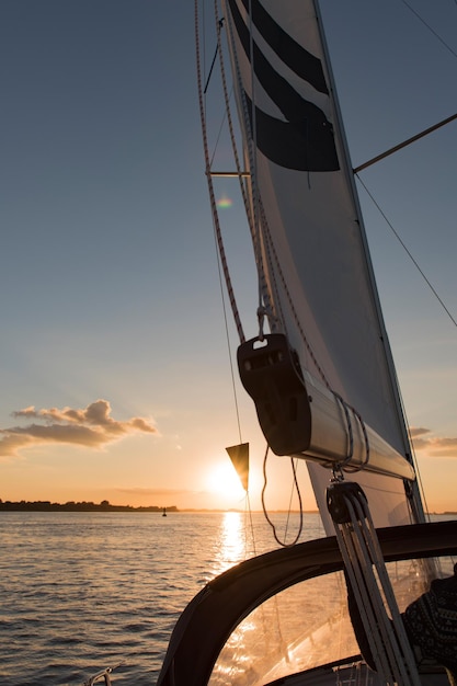 Velero navegando en el mar contra el cielo durante la puesta de sol