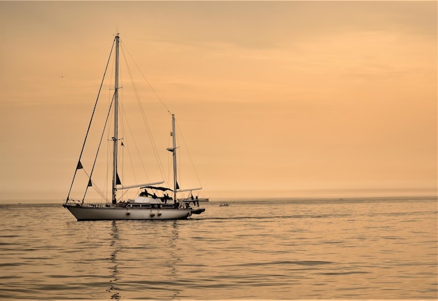 Velero navegando en el mar contra el cielo durante la puesta de sol