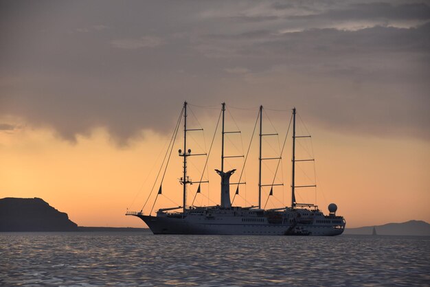 Foto velero navegando en el mar contra el cielo durante la puesta de sol