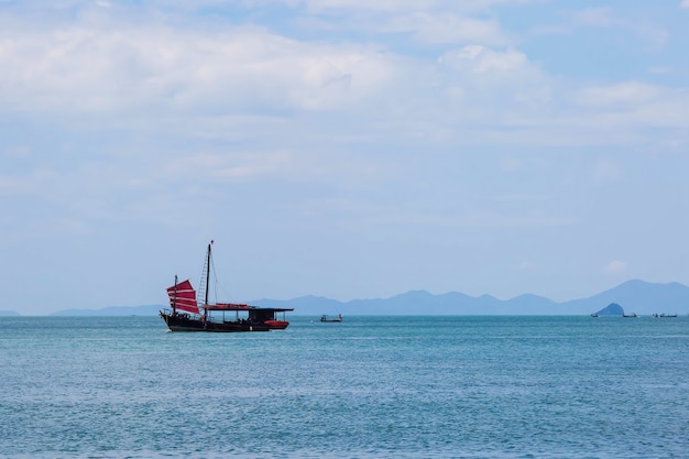 Velero negro con velas rojas navegando en el mar azul