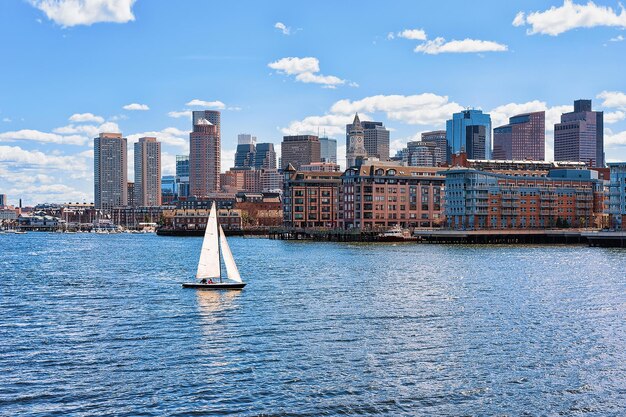 Velero que viaja a través del río Charles con el horizonte de la ciudad al fondo en Boston, Estados Unidos