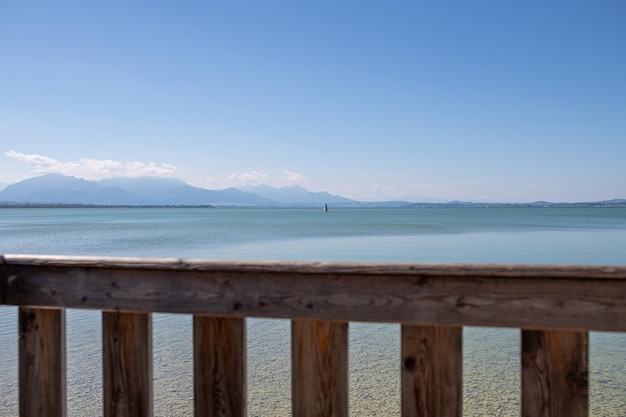 Velero solitario detrás de la baranda de madera en el lago chiemsee