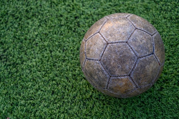 Velha bola de futebol no gramado verde