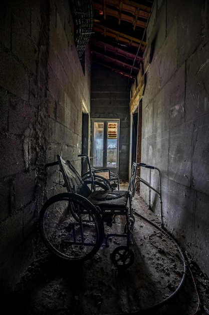 Foto velha cadeira de rodas numa casa abandonada.