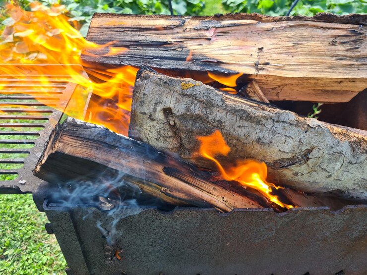 Foto velha grelha de churrasco com troncos de madeira queimando fogo aberto de uma caixa de metal lanche ao ar livre em um parque natural
