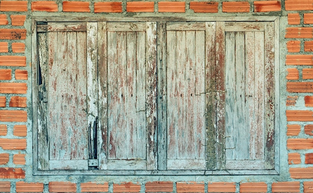 velha janela de madeira marrom com tijolos de parede marrom
