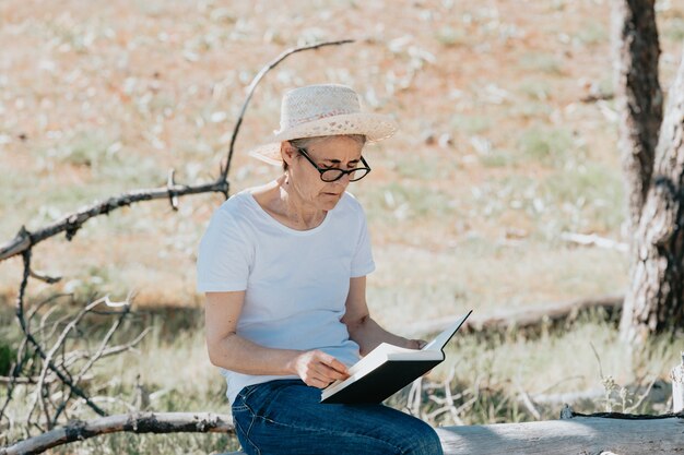 velha lendo um livro na praia durante um dia super ensolarado relaxe e relaxe com liberdade.