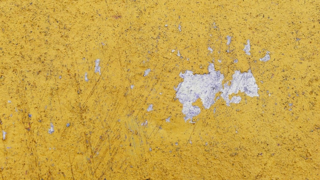 Velha parede de cimento descascada fundo de textura exterior com cor amarela pintura descascada de baixa qualidade parede rachada