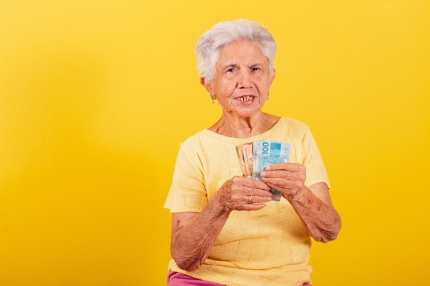 Foto velha senhora segurando notas de dinheiro salário aposentadoria economia e conceito de finanças