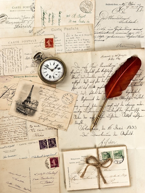 Foto velhas cartas e cartões postais com pena de pena e relógio vintage. fundo nostálgico