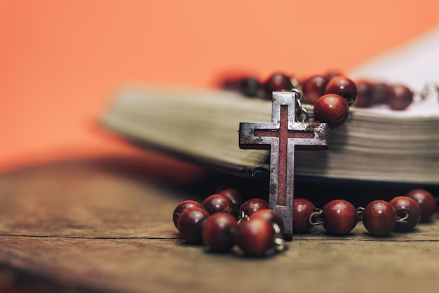 Velhas contas vermelhas e crucifixo em uma Bíblia Belos corais fundo laranja conceito de religião