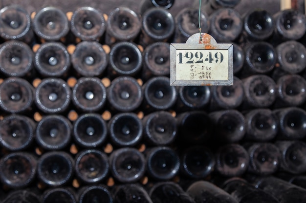 Foto velhas garrafas de vinho empoeiradas escuras em linhas na adega