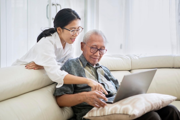 Velho aprendendo a usar um laptop com sua filha