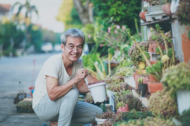 Foto velho asiático cuidando da planta de casa no jardim de casa