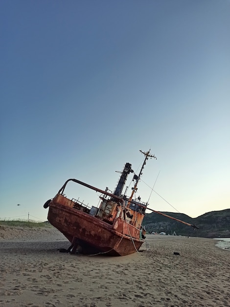 Velho barco de pesca em ruínas à beira-mar.