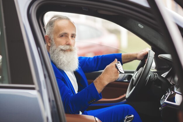 Velho bonito dentro do carro. macho maduro barbudo no automóvel. empresário confiante, comprando o carro.