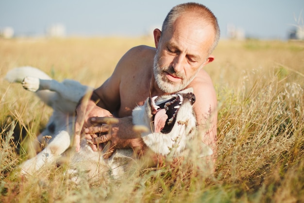 Foto velho brincando com seu cachorro husky siberiano