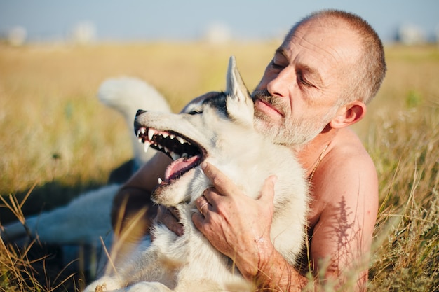 Velho brincando com seu cachorro Husky Siberiano