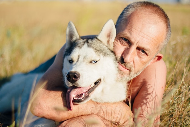 Foto velho brincando com seu cachorro husky siberiano