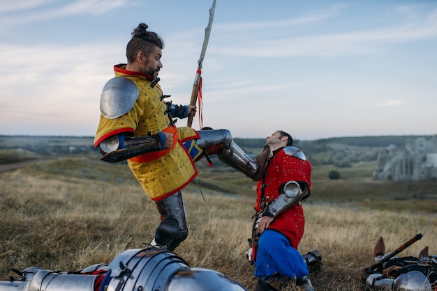 Velho cavaleiro medieval em armadura se prepara para cortar a cabeça, grande batalha. Antigo guerreiro com armadura posando no campo