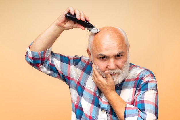 Velho com máquina de cortar cabelo, corte de cabelo com barbeador elétrico.