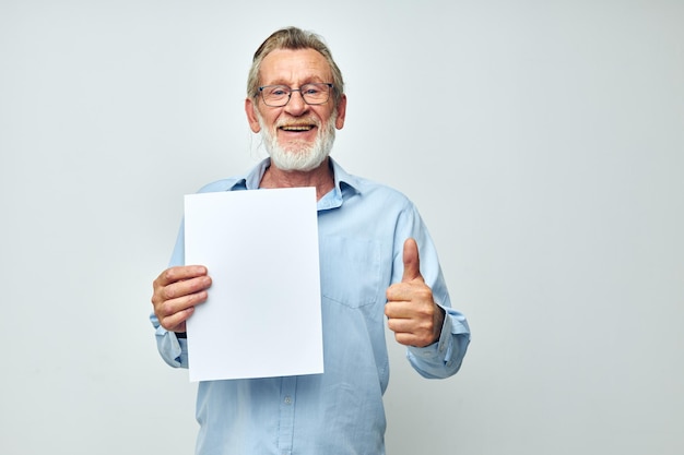 Velho de camisa azul e óculos uma folha branca de papel de fundo claro