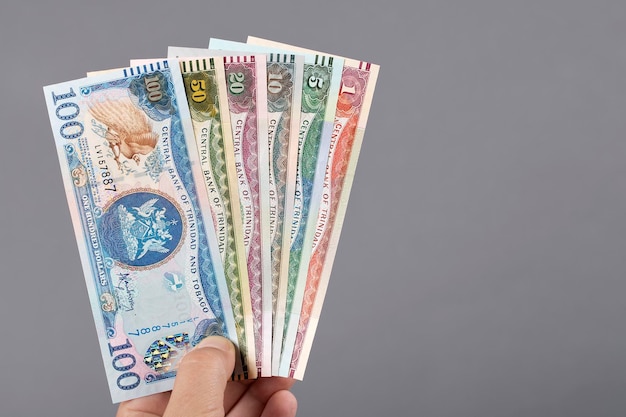 Velho dinheiro de Trinidad e Tobago na mão sobre um fundo cinza
