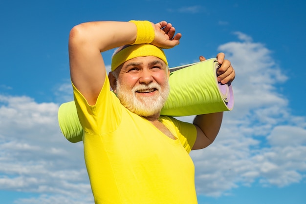 Velho feliz e ativo segurando uma esteira de exercícios