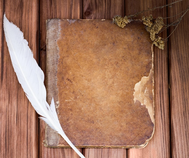 Velho livro gasto com uma pena em uma mesa de madeira