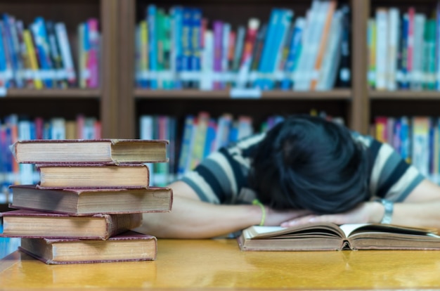 Velho livro sobre a mesa na biblioteca com o homem dormindo sobre o fundo do livro