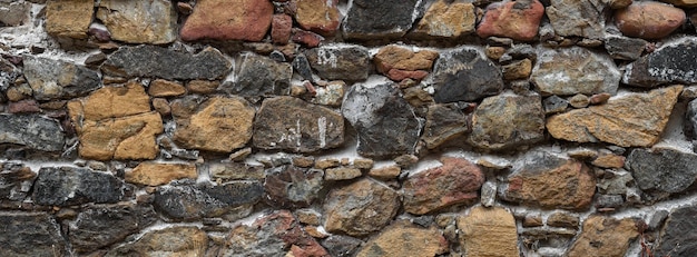 Velho muro áspero de pedra natural multicolorida. textura de construção abandonada