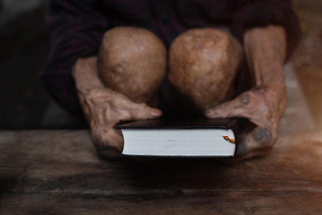 Velho segura a bíblia nas mãos Lendo a Bíblia Sagrada em casa Conceito de espiritualidade de fé e religião Esperança de paz