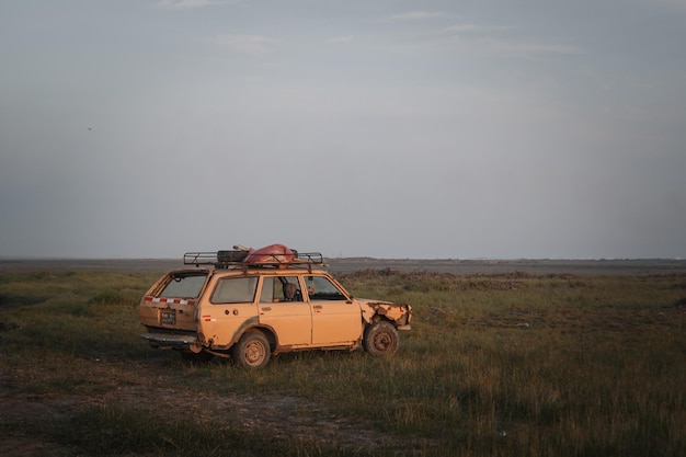 Vello coche en el campo contra el cielo durante la puesta de sol